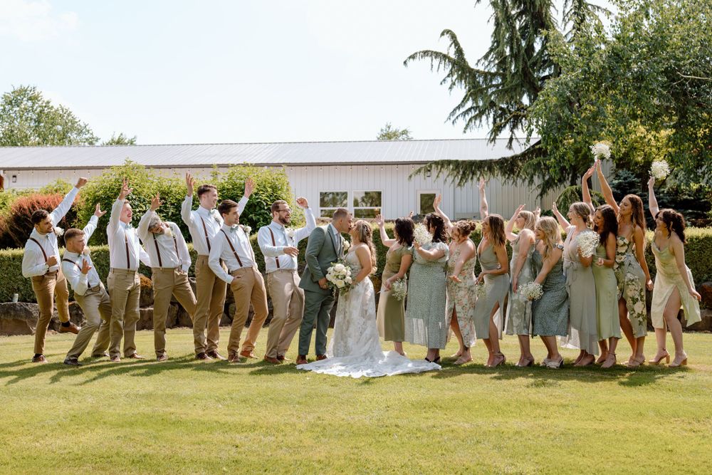 Bridal party celebrating as bride and groom kiss in the middle