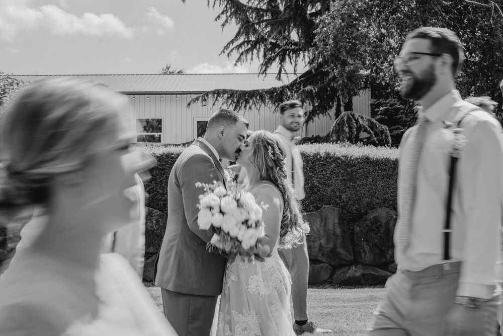 Black and white of bride and groom kissing with blurry bridal party