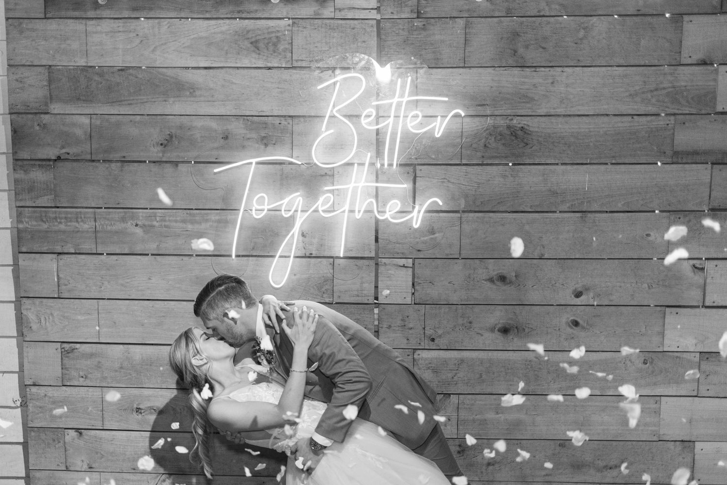 Romantic black and white photo of couple beneath illuminated Better Together neon sign.