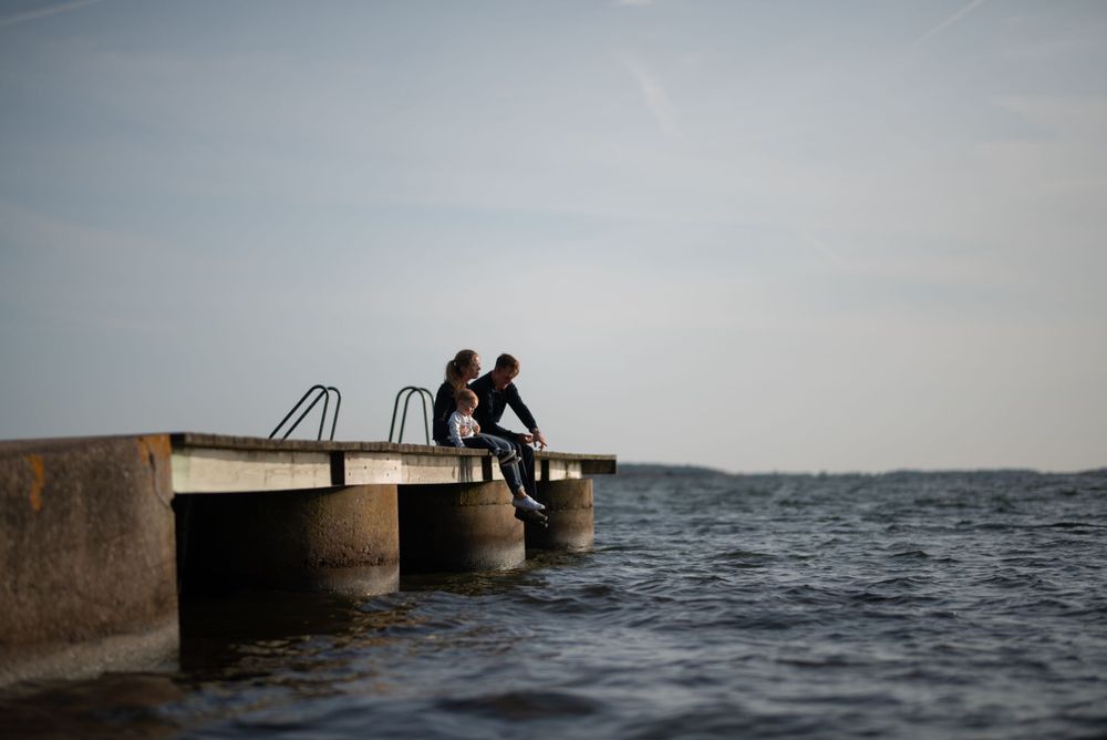 Two people sitting together on concrete pier edge at sunset.