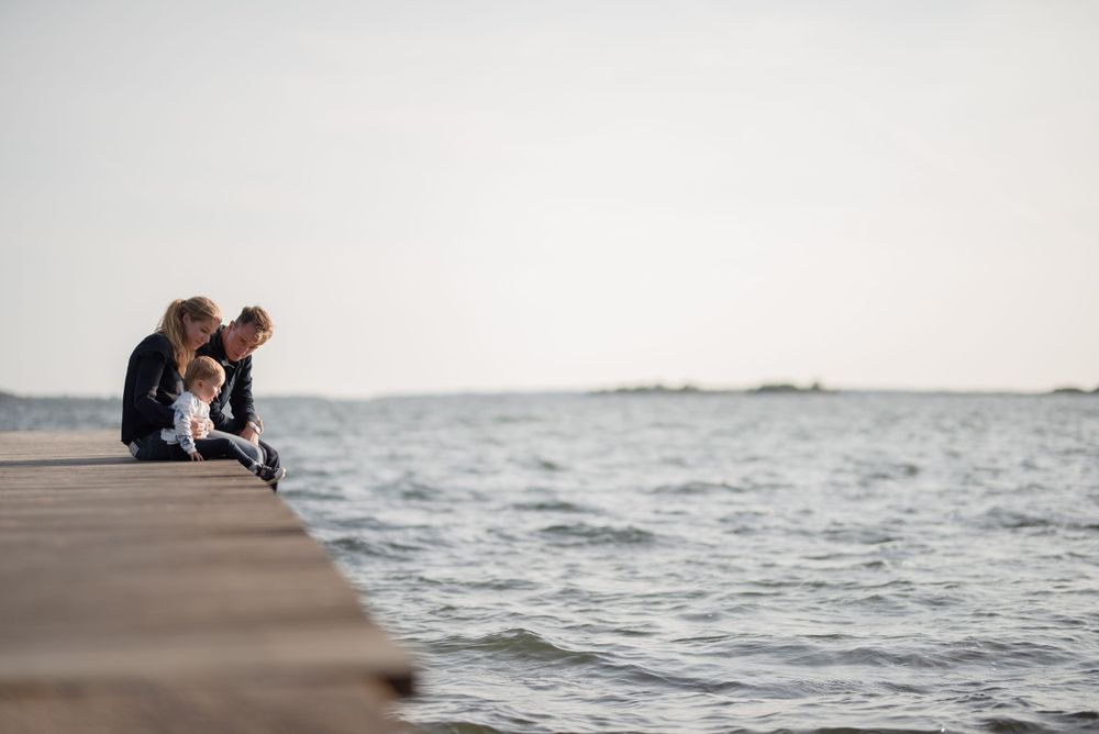 Small group sitting on edge of pier looking out over water.