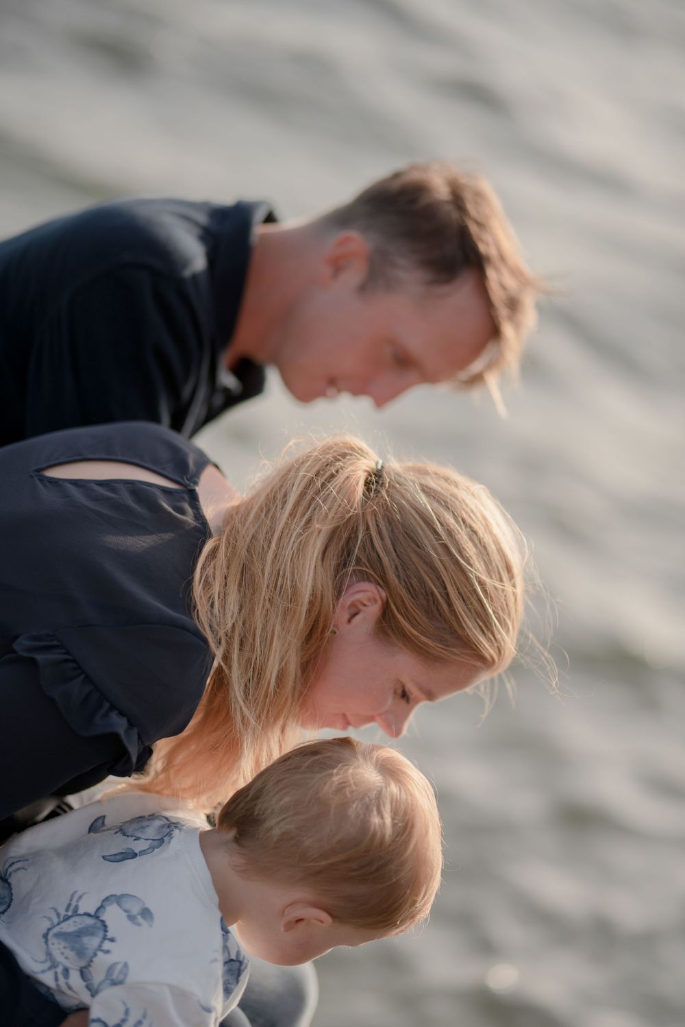 Family members share an intimate moment leaning together outdoors in a candid pose.