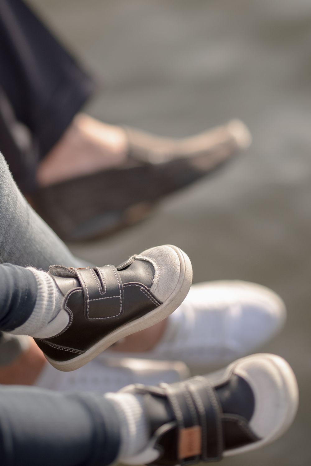 Close-up of children's shoes and feet dangling over water.