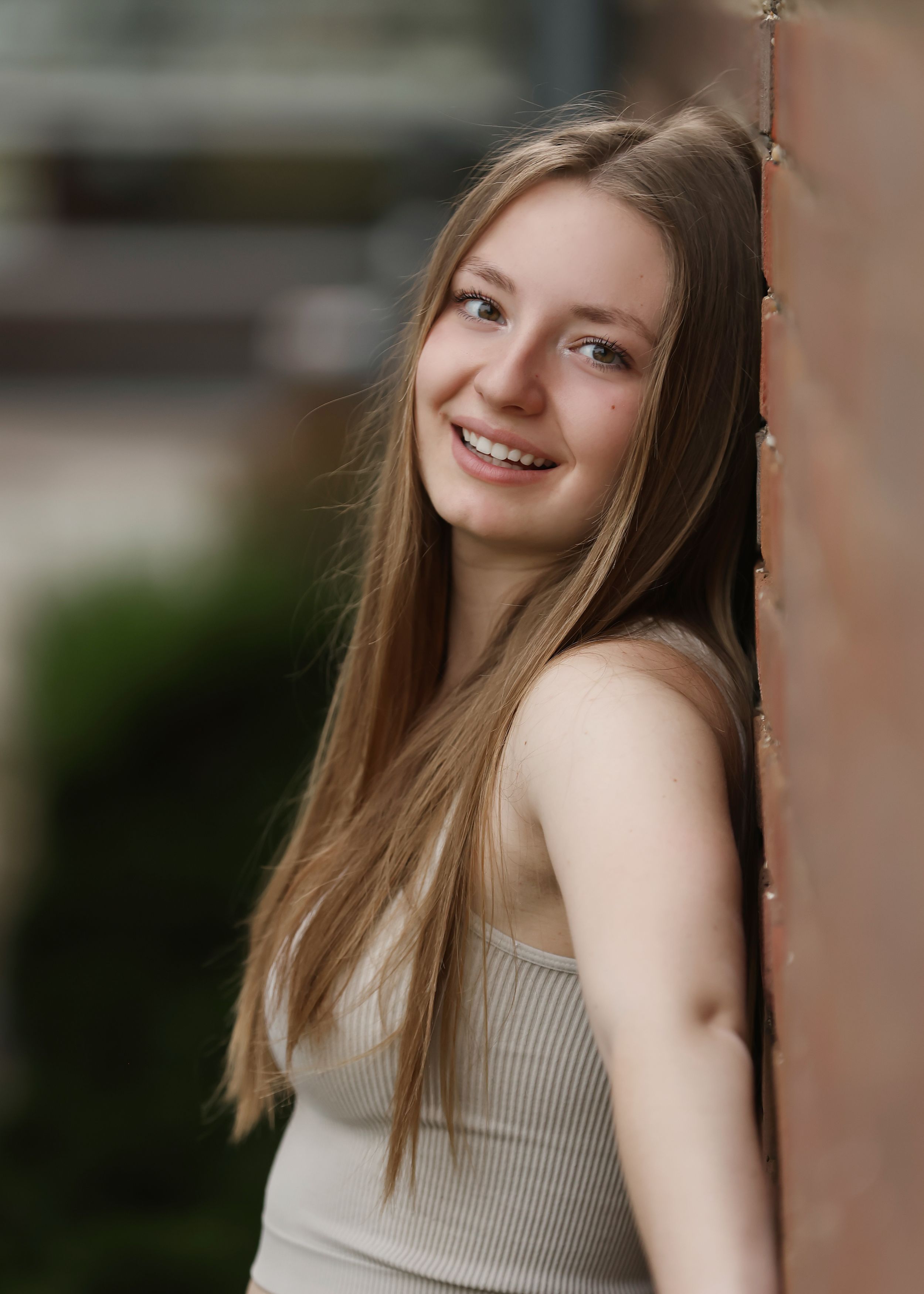 Natural light portraits against textured brick wall in casual attire.