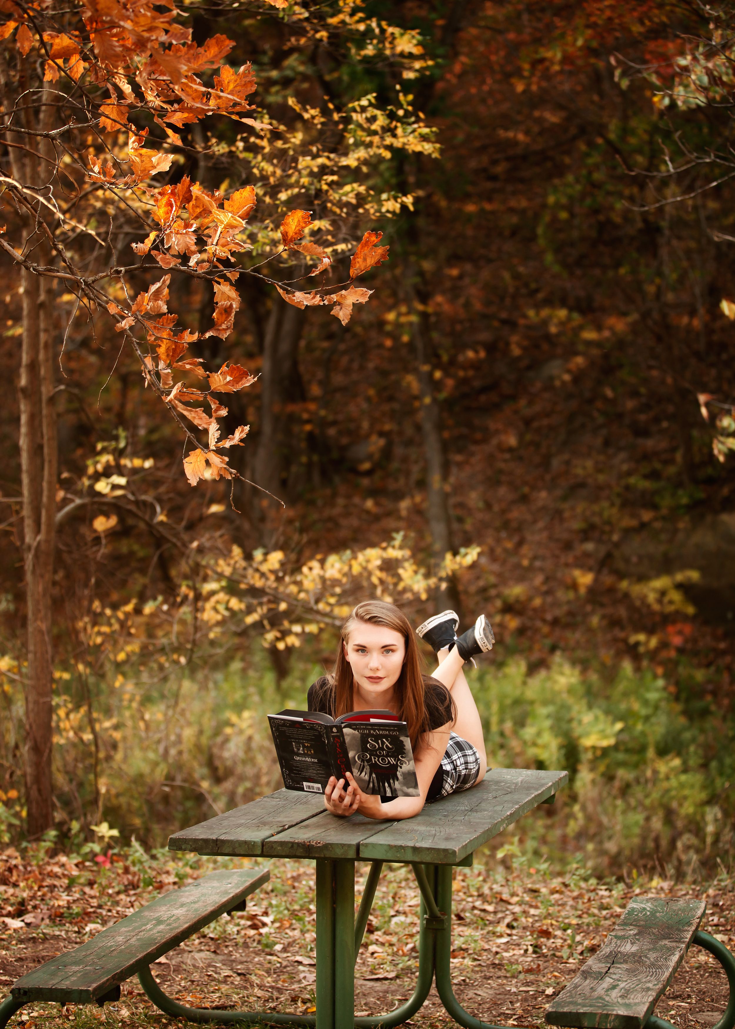 Rustic picnic table in a wooded area surrounded by fall foliage.