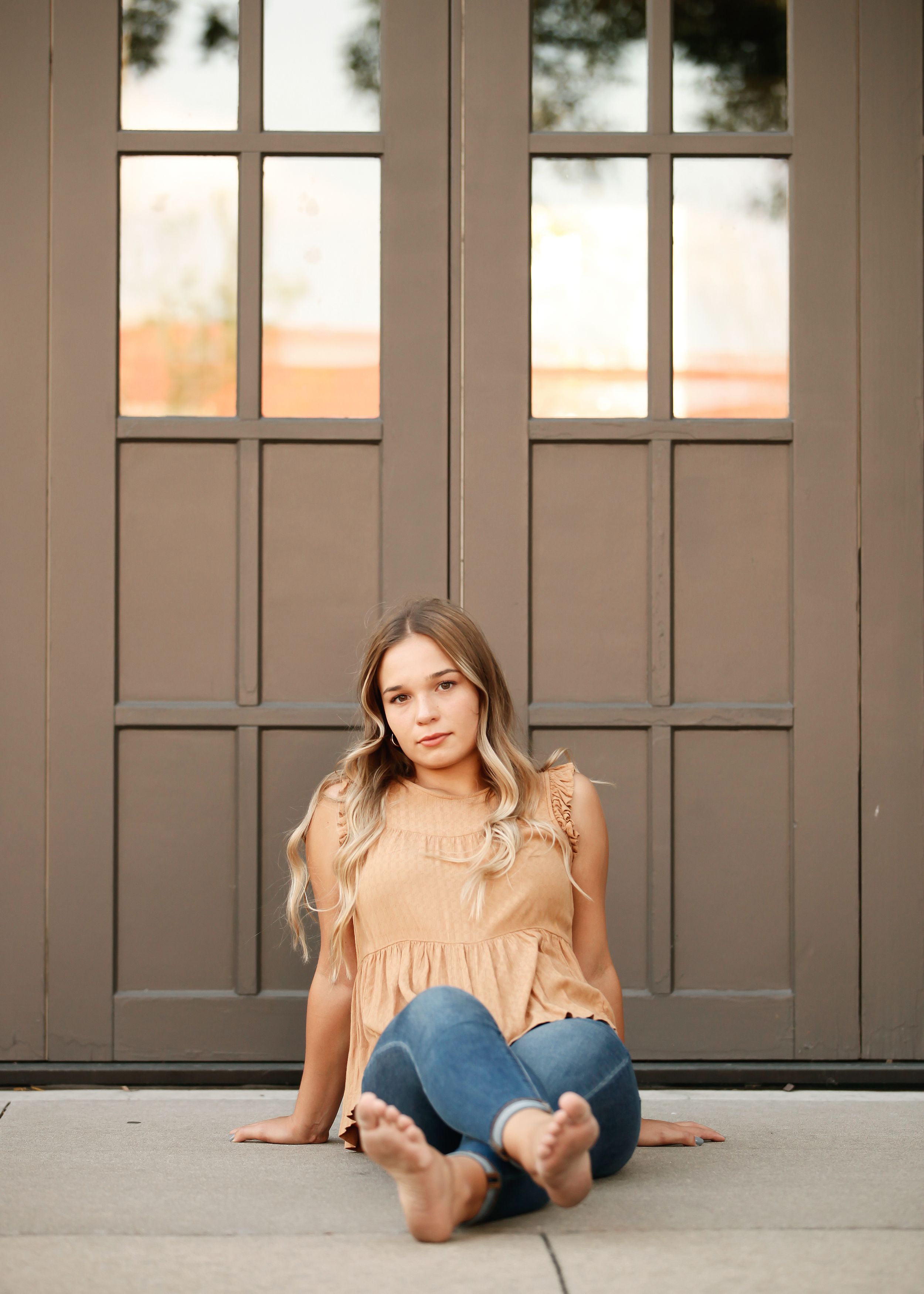Creative floor poses against dark paneled doors in natural lighting.