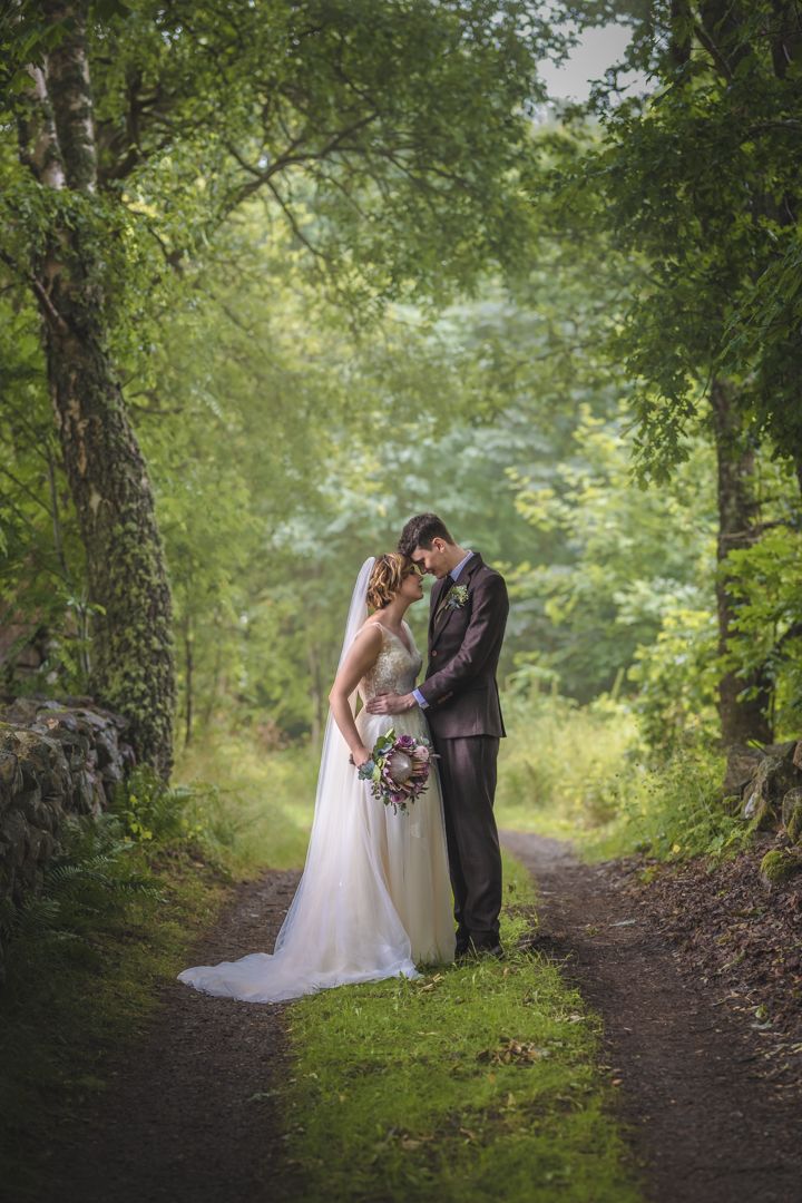Bröllopsfotografering på Rya kyrkoruin Eket i Skåne.  Brudpar står i en sagolik skog