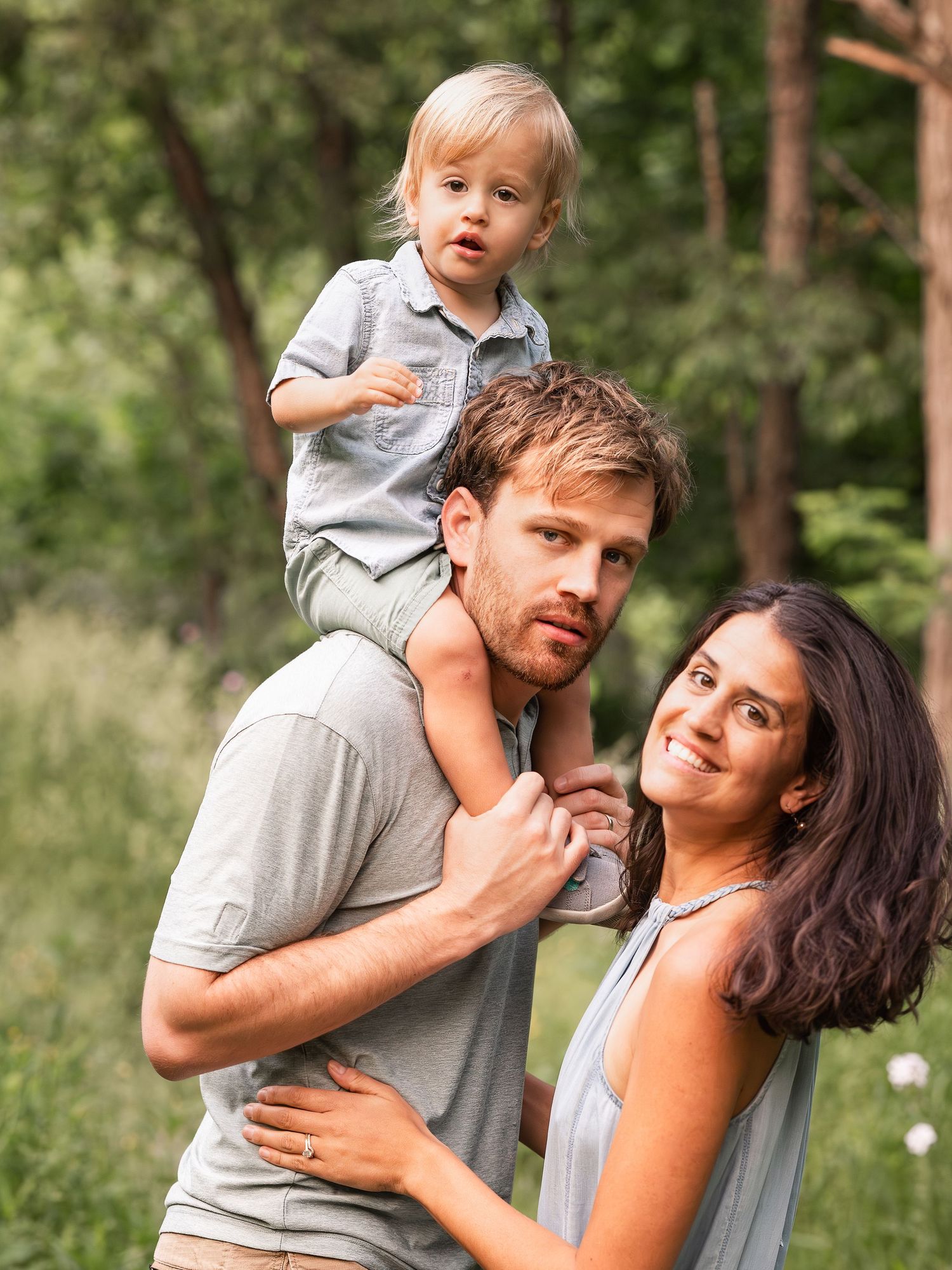 Family of three with boy on shoulders looking back at camera