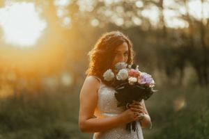 A radiant bride holding a beautiful bouquet under the warm sun on her special day.