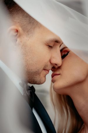 A couple sharing a romantic moment, kissing passionately under a beautiful veil. Love is in the air!