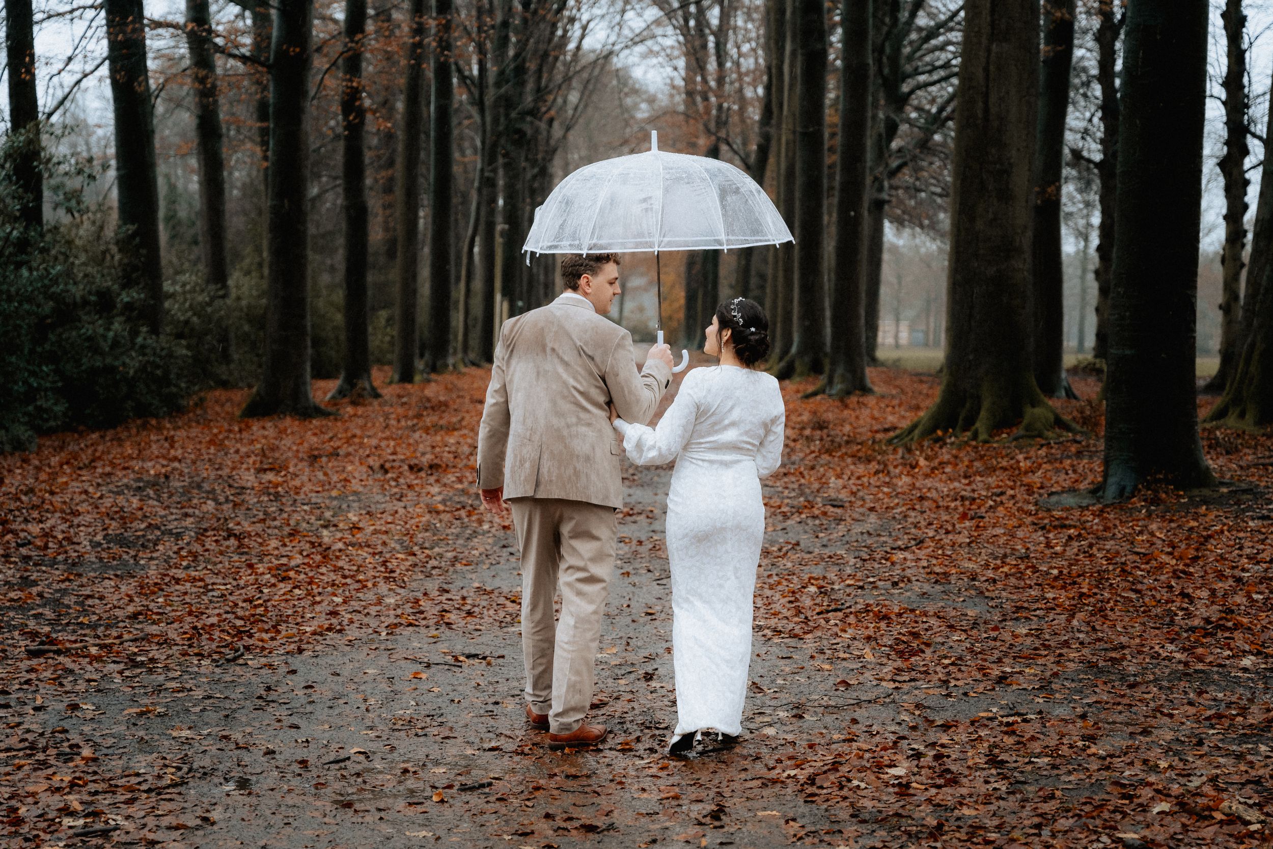 A happy couple strolling through a serene forest, hand in hand, on their special day.