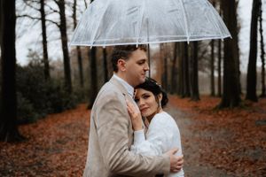 A beautiful wedding couple embracing under the rain, sharing a romantic moment filled with love and joy.