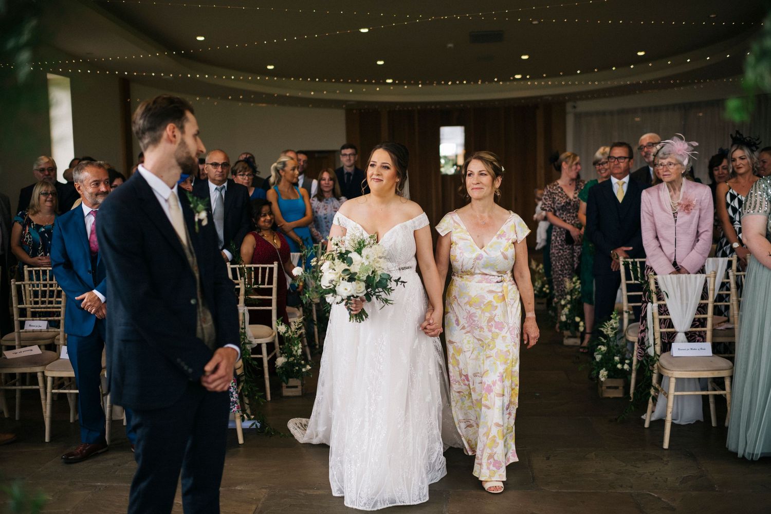 Spacious wedding venue with guests seated at round tables during an indoor celebration.