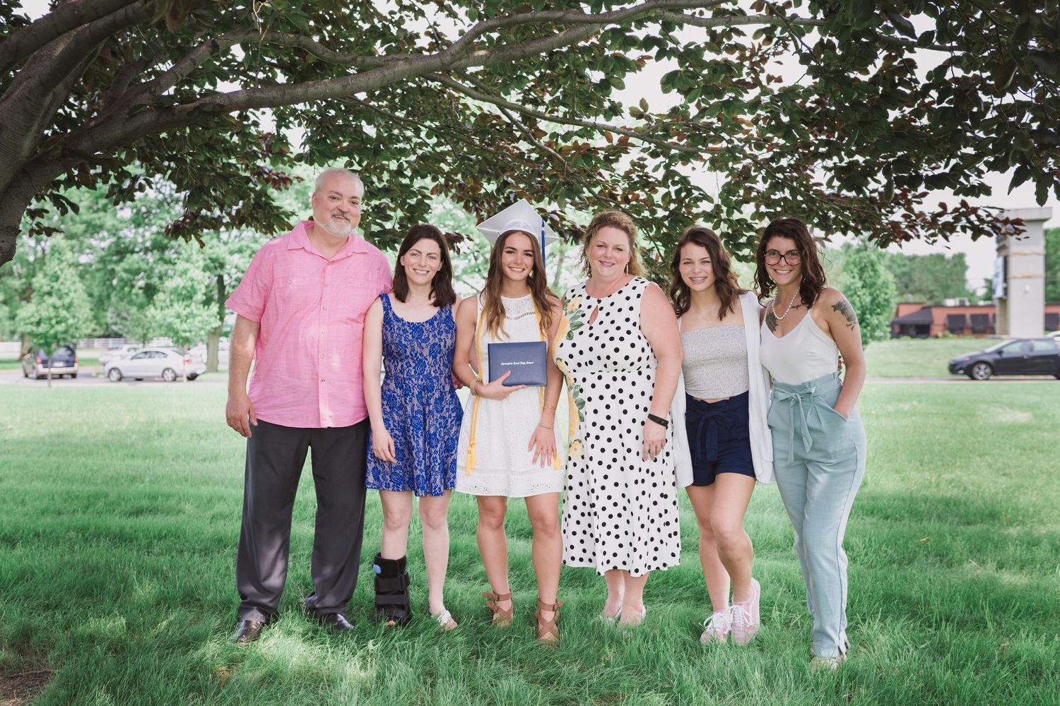 Group of friends posing together outdoors on a grassy lawn during summer.