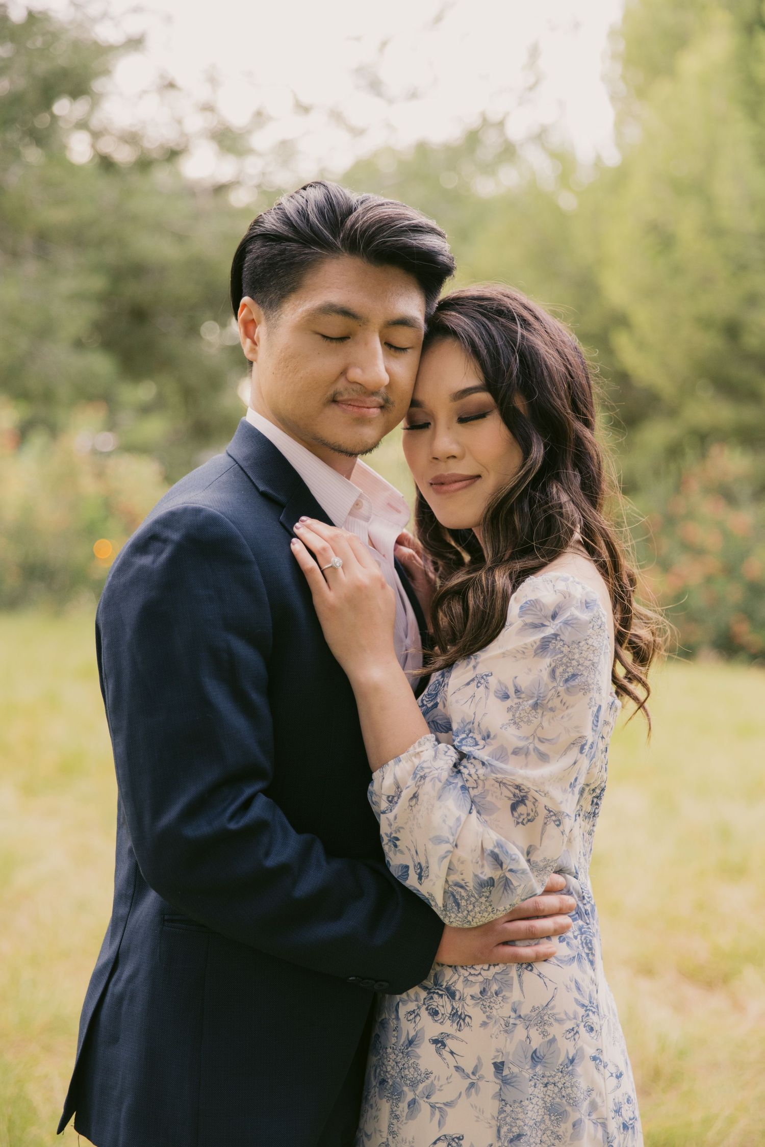 Intimate embrace captured in soft natural light with delicate floral dress details.