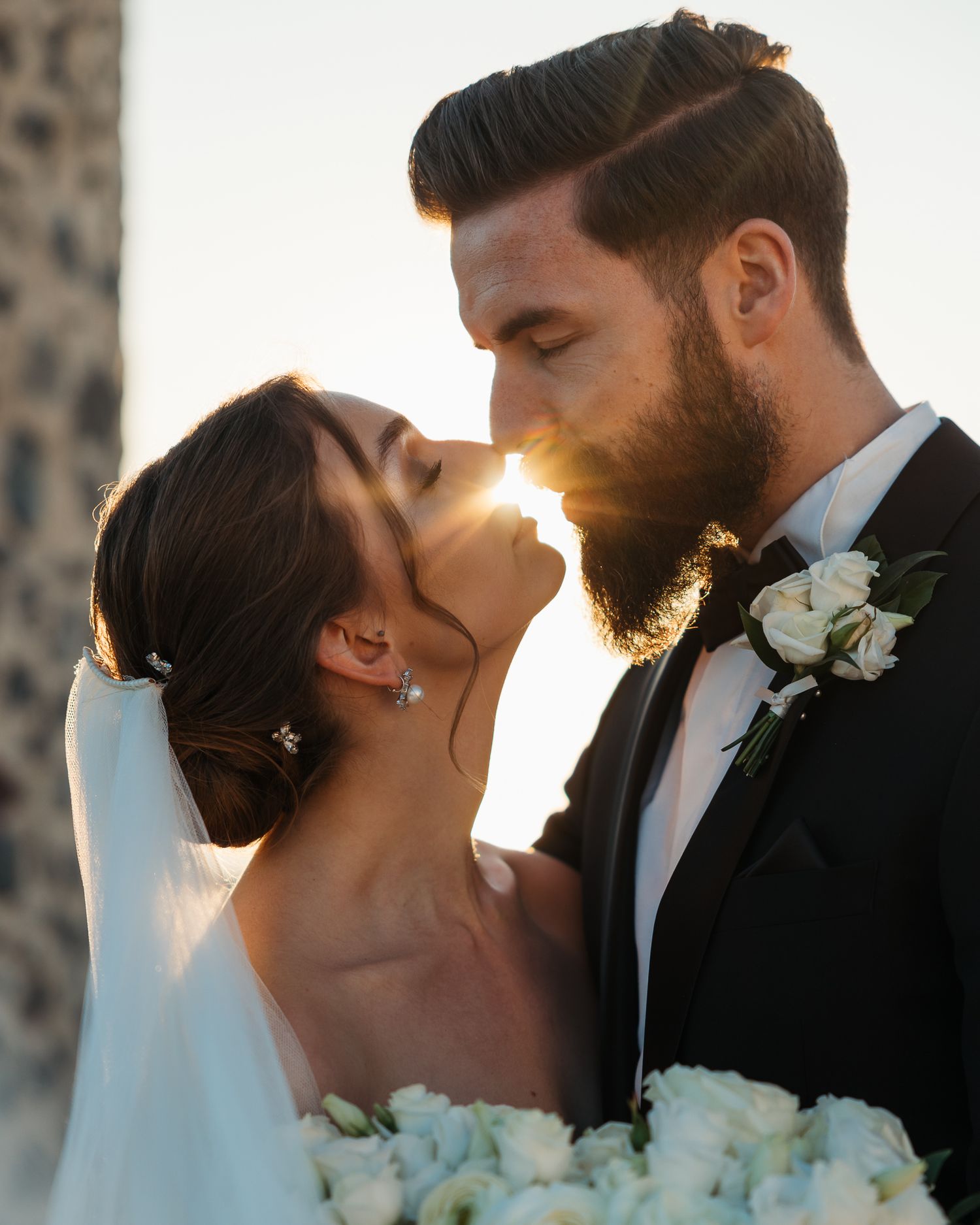 Romantic sunset silhouette of wedding couple sharing intimate moment with flowers at a wedding in Santorini.