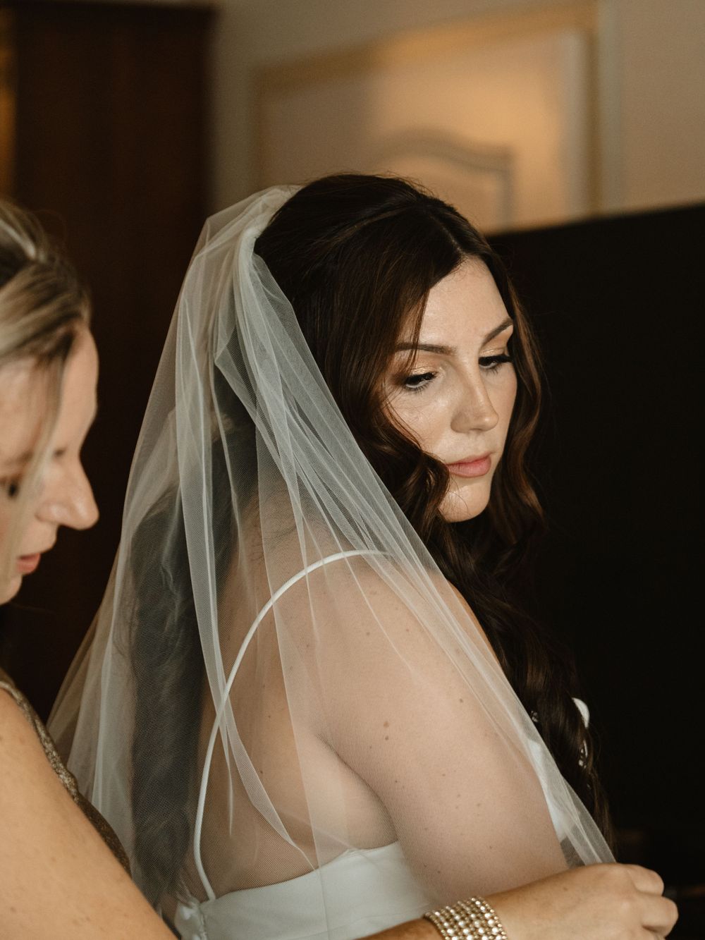 A close-up side profile of someone wearing a delicate wedding veil and white dress.