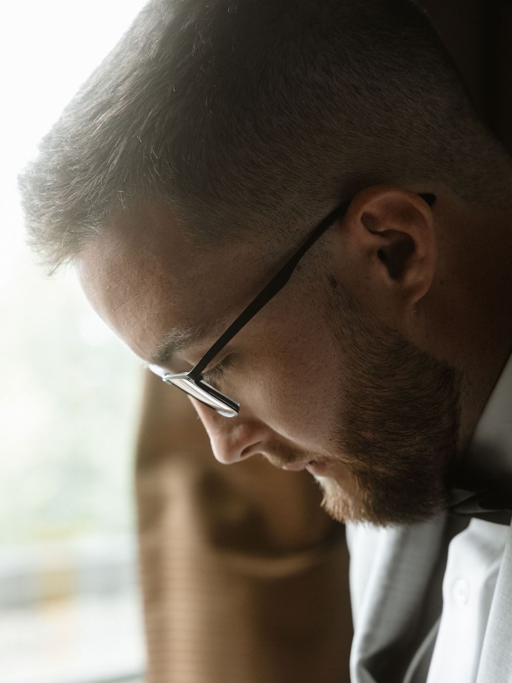 Side profile view of someone in glasses looking down thoughtfully.