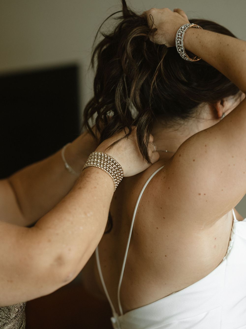 Close-up shot of someone adjusting jewelry and hair while wearing a white dress.