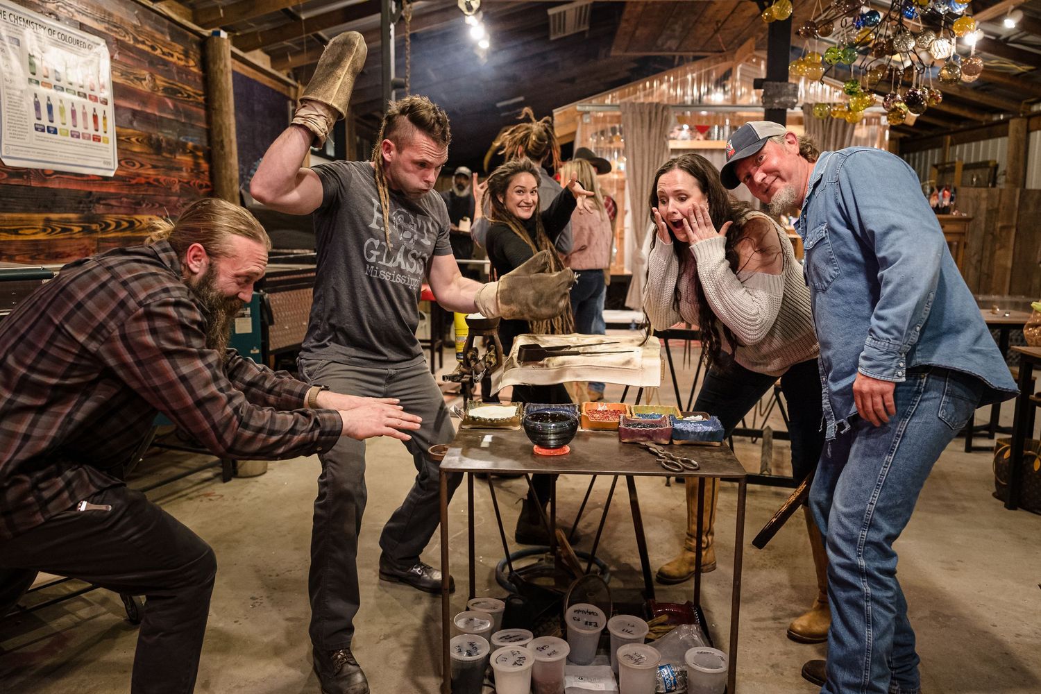 Group of people interacting at tables inside a cozy wooden barn or rustic venue space.