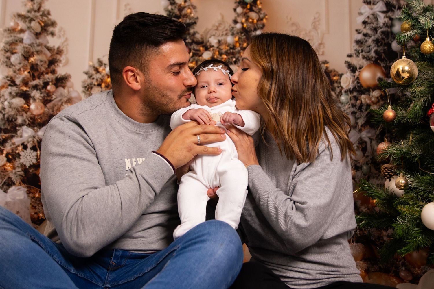 Holiday family portrait with matching grey sweaters in front of Christmas tree.