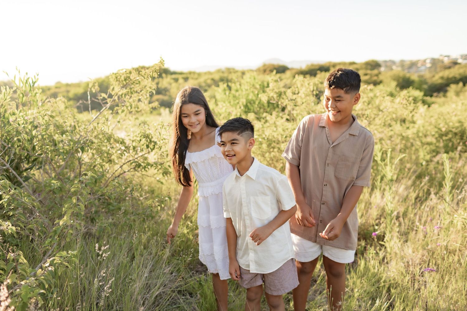 Candid photo of group walking through tall grass in coordinated white and beige outfits.