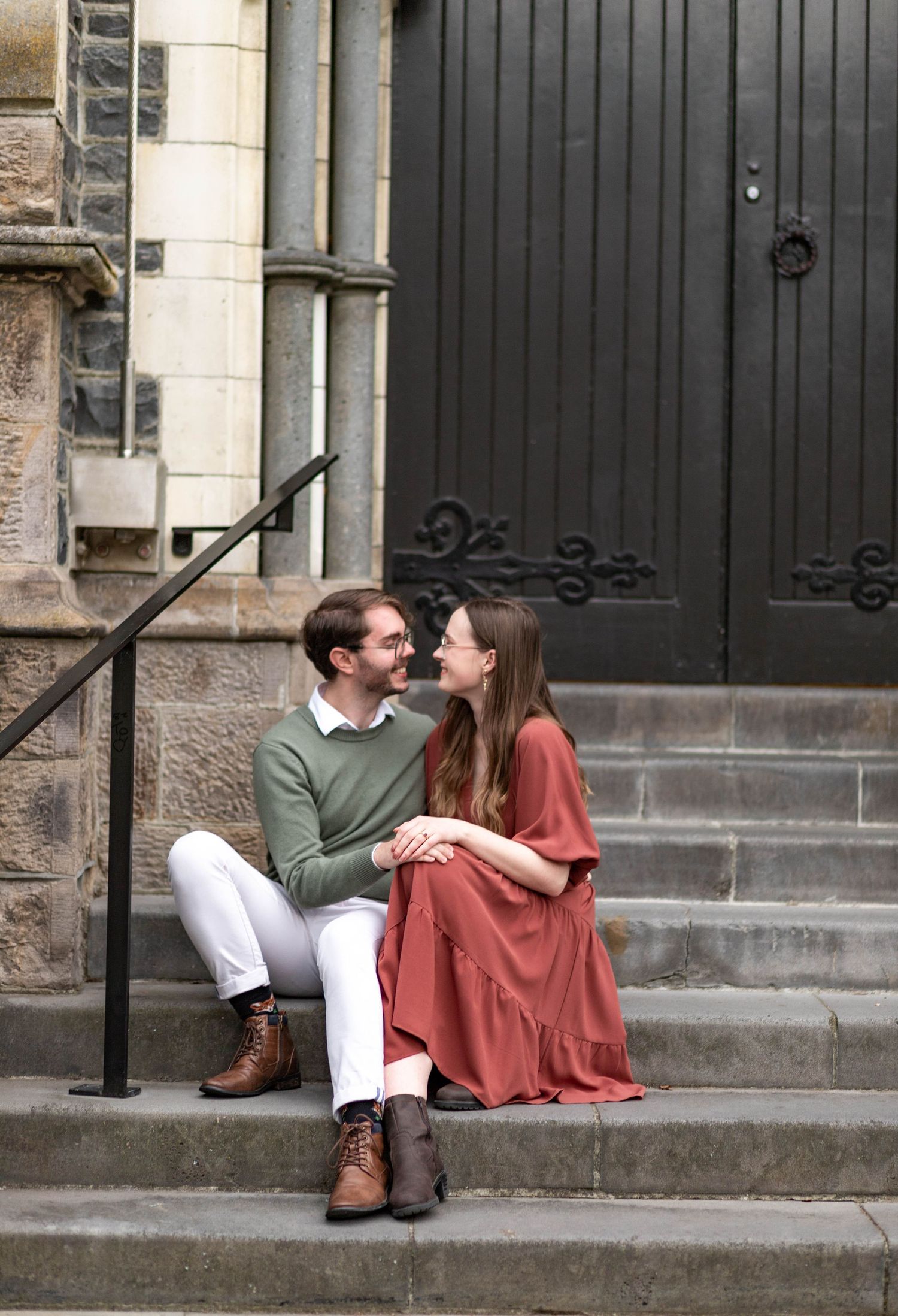 couple sitting on steps leaning into one another with their hands rested on top of each other