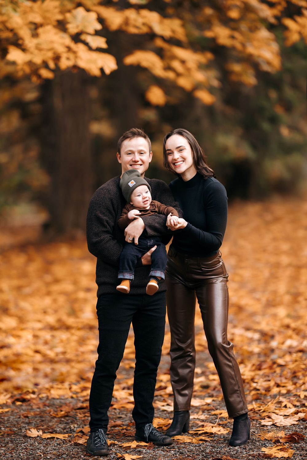 Family portrait in autumn forest with golden leaves in background.
