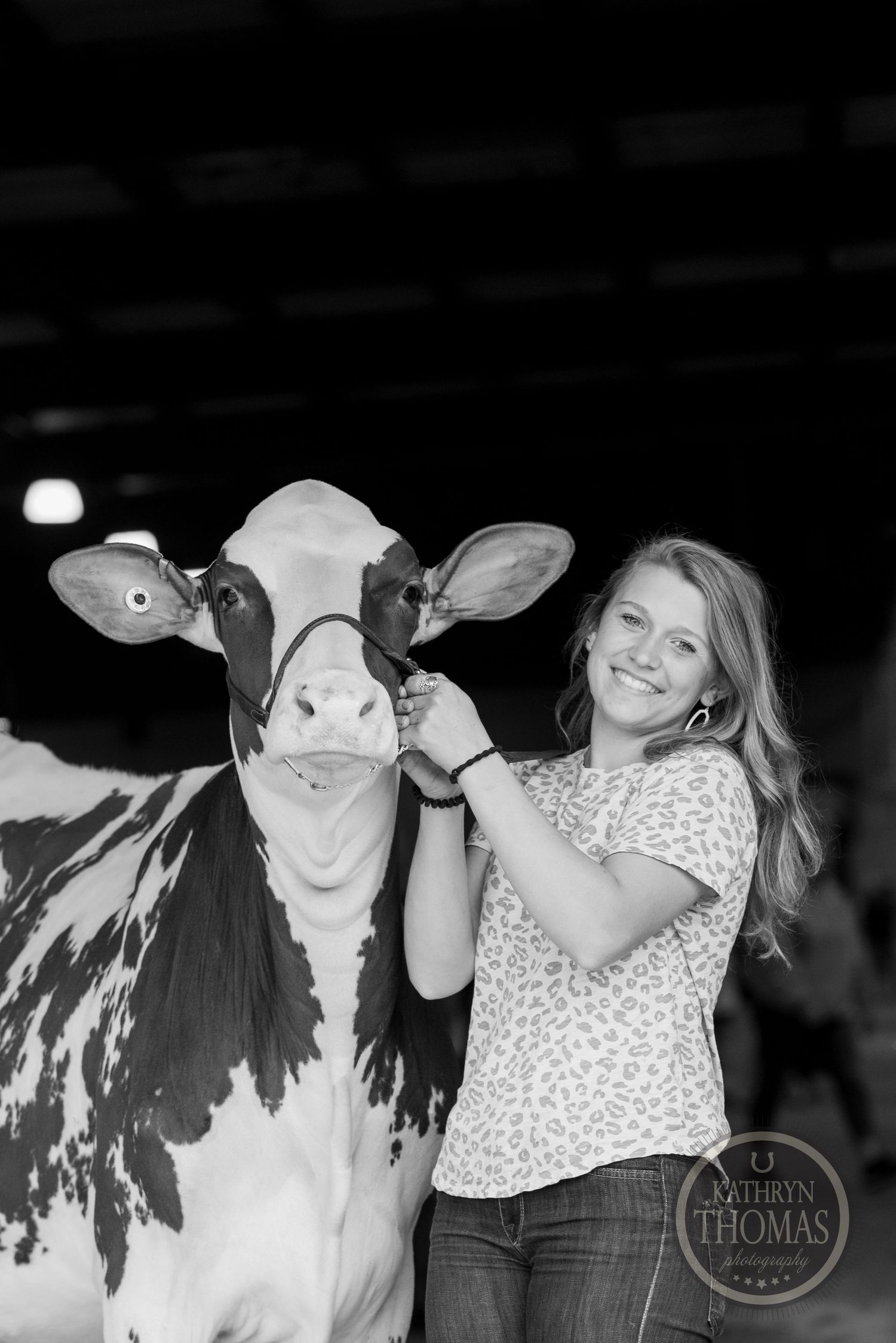 A black and white portrait captures a joyful moment between a handler and dairy cow.