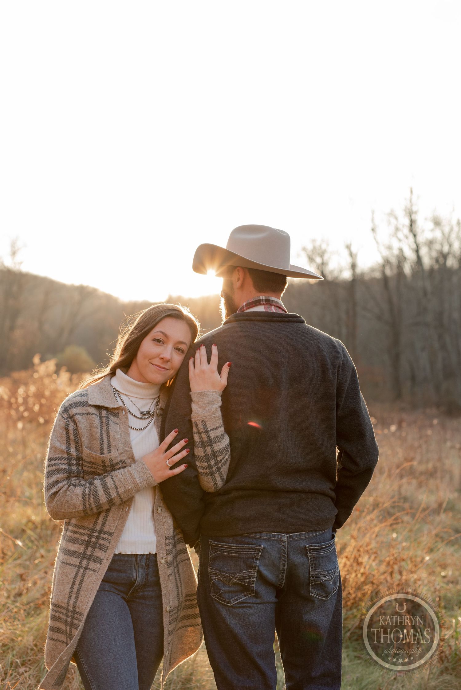 A couple shares a tender moment in golden sunlight wearing autumn attire.