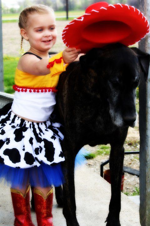 Colorful tutu dress and red boots next to a black dog in a park setting.