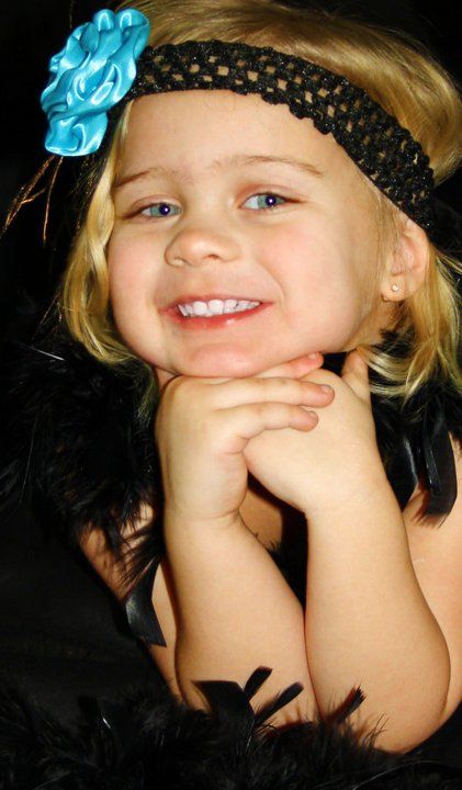 Portrait with a bright blue bow headband against dark background.