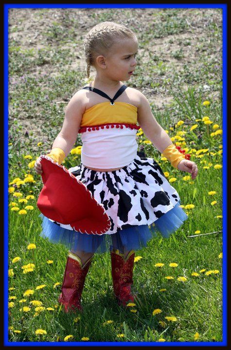 Colorful tutu dress with cow print and red boots in a field of dandelions.