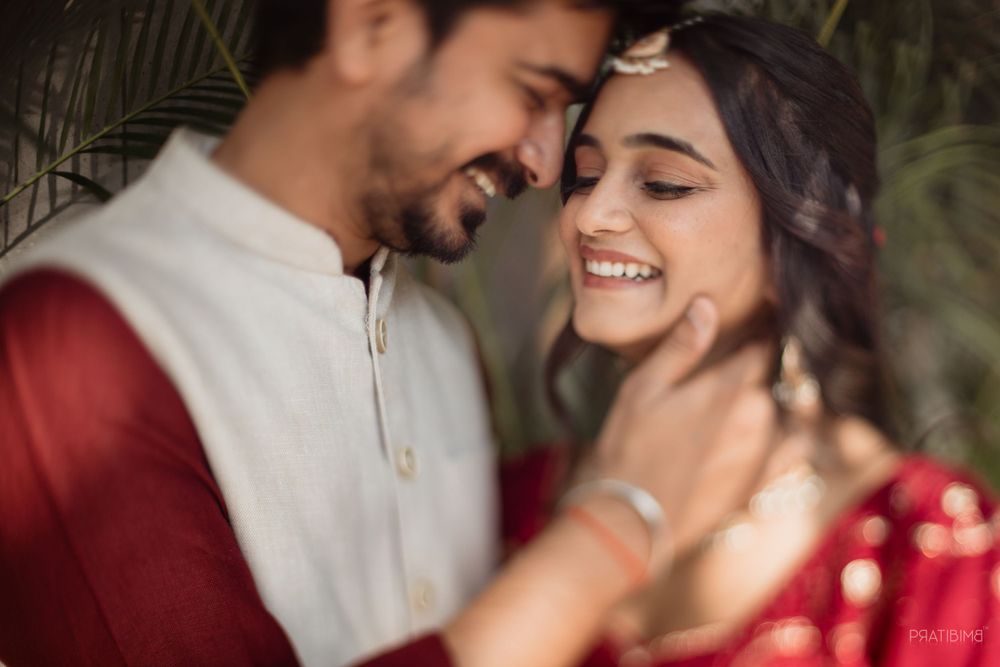 Intimate moment captured between couple in traditional Indian wedding attire.