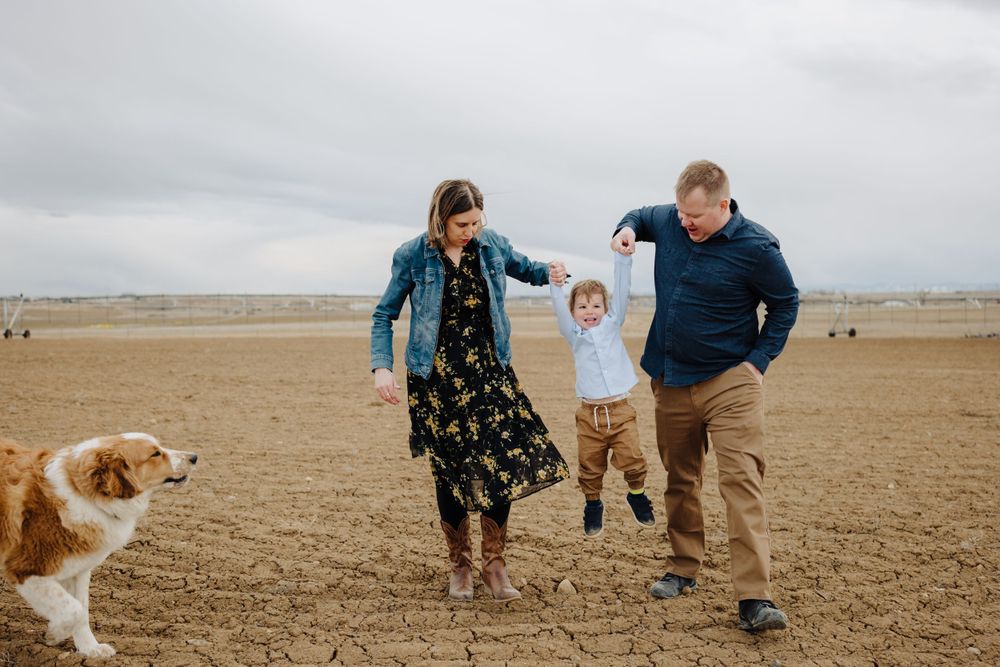 Family walking together in an open field with their golden retriever dog.