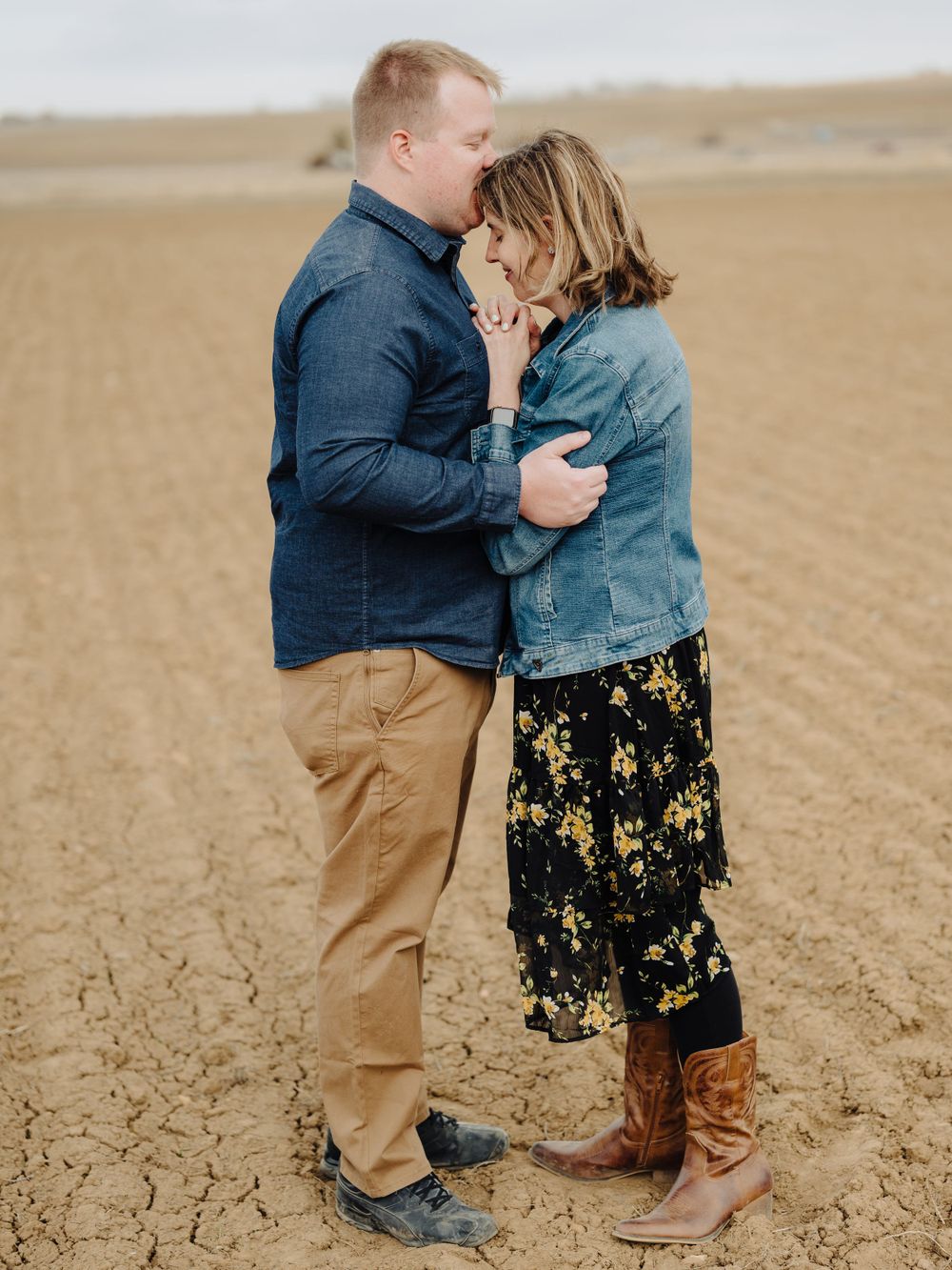 Couple sharing an intimate moment in a desert landscape while wearing casual attire.