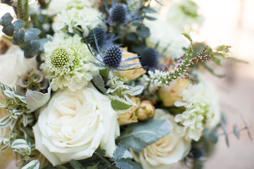 Elegant wedding bouquet with white roses and blue thistle flowers.