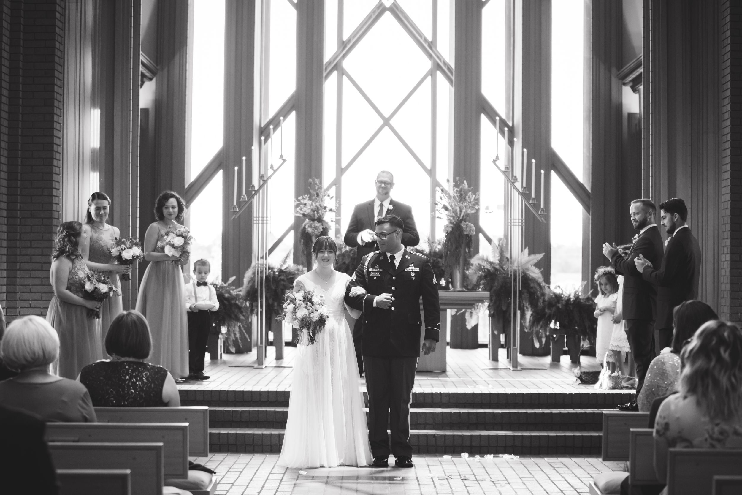 Black and white wedding ceremony photos inside a grand church with dramatic lighting and architecture.