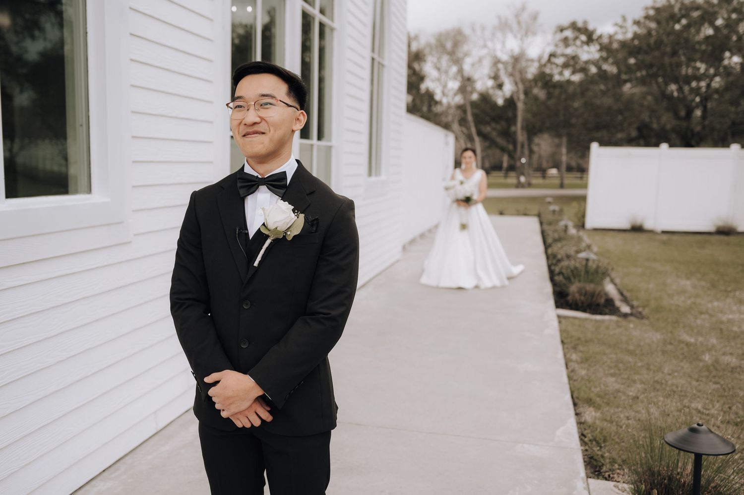 A wedding day first look moment captured outside a white chapel building.
