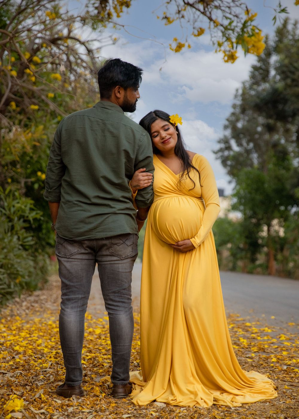 Couple shares intimate moment on path with yellow fallen leaves and autumn trees.