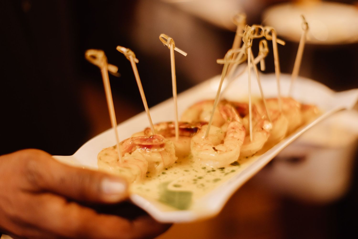 Appetizers served on wooden skewers displayed on a white serving platter.
