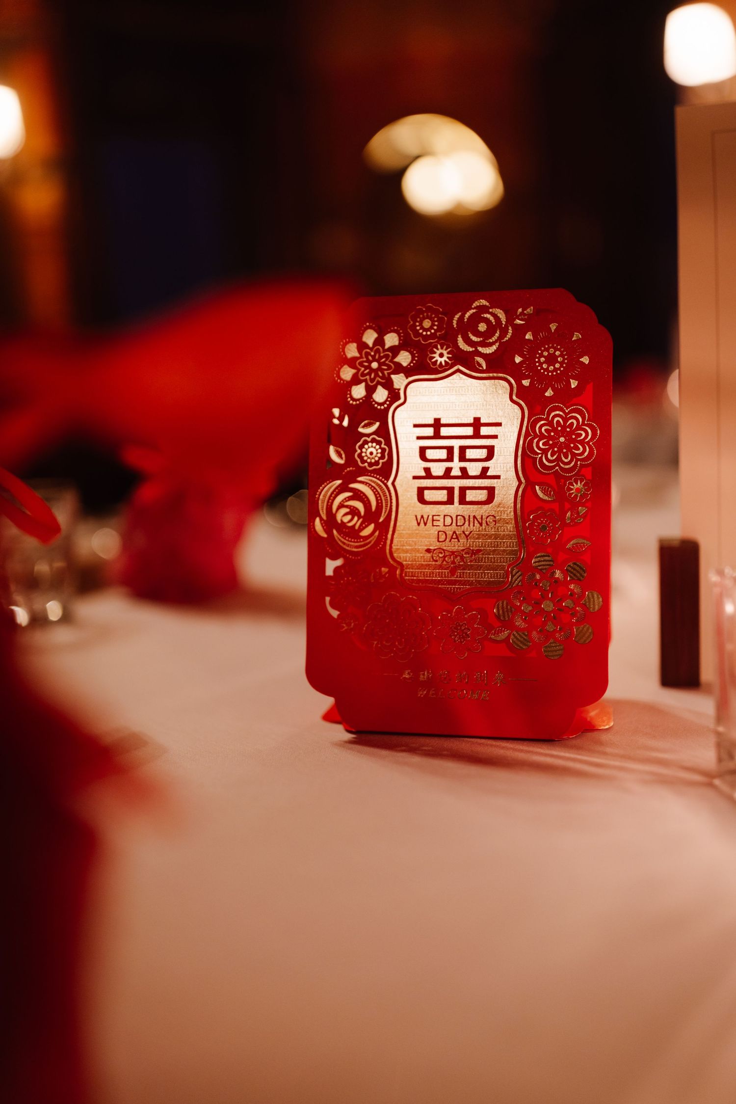 A traditional red Chinese double happiness wedding card illuminated by candlelight.