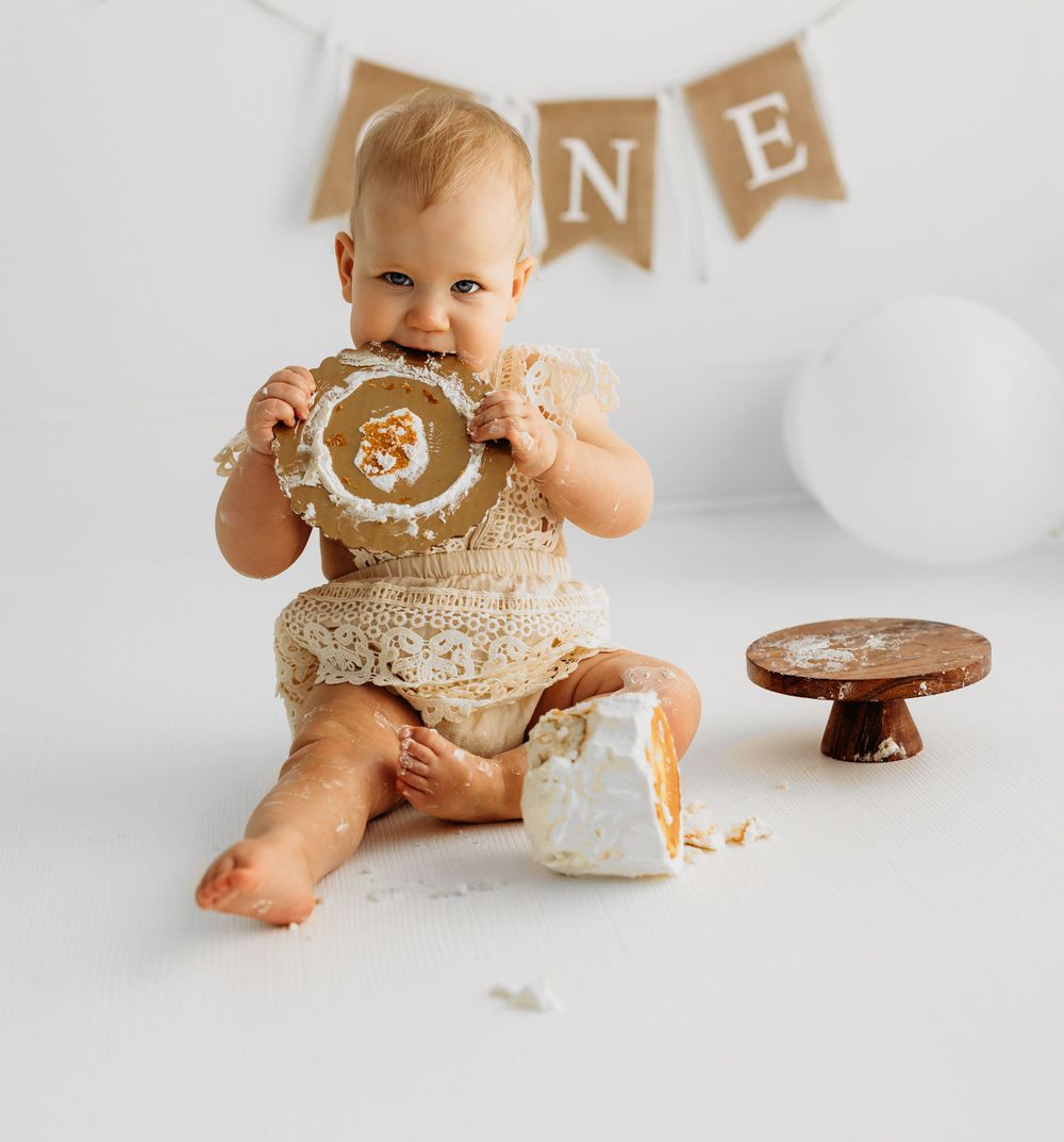One year old cake smash photo with baby in sequin outfit enjoying birthday dessert. during a session in Fairfax, VA.