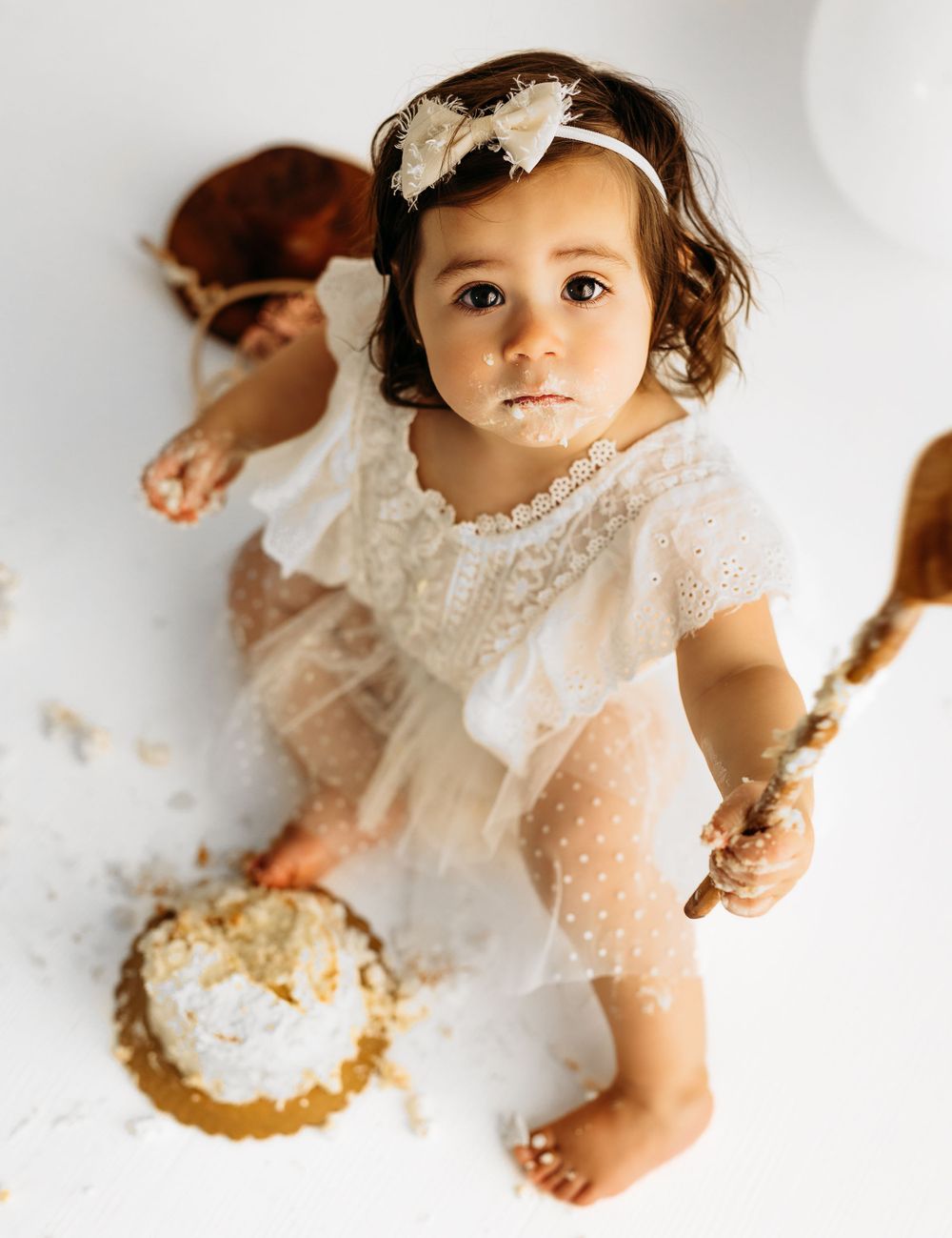 First birthday cake smash session with toddler in lace dress and floral headband. during a session in Fairfax, VA.