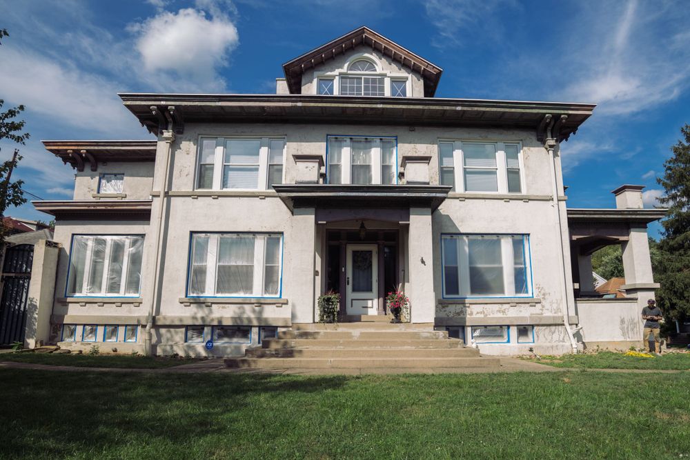 Large gray craftsman style house with white trim and columned front porch.