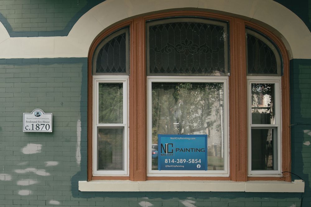 Arched window frame with wooden trim on light blue painted exterior wall of historic building.