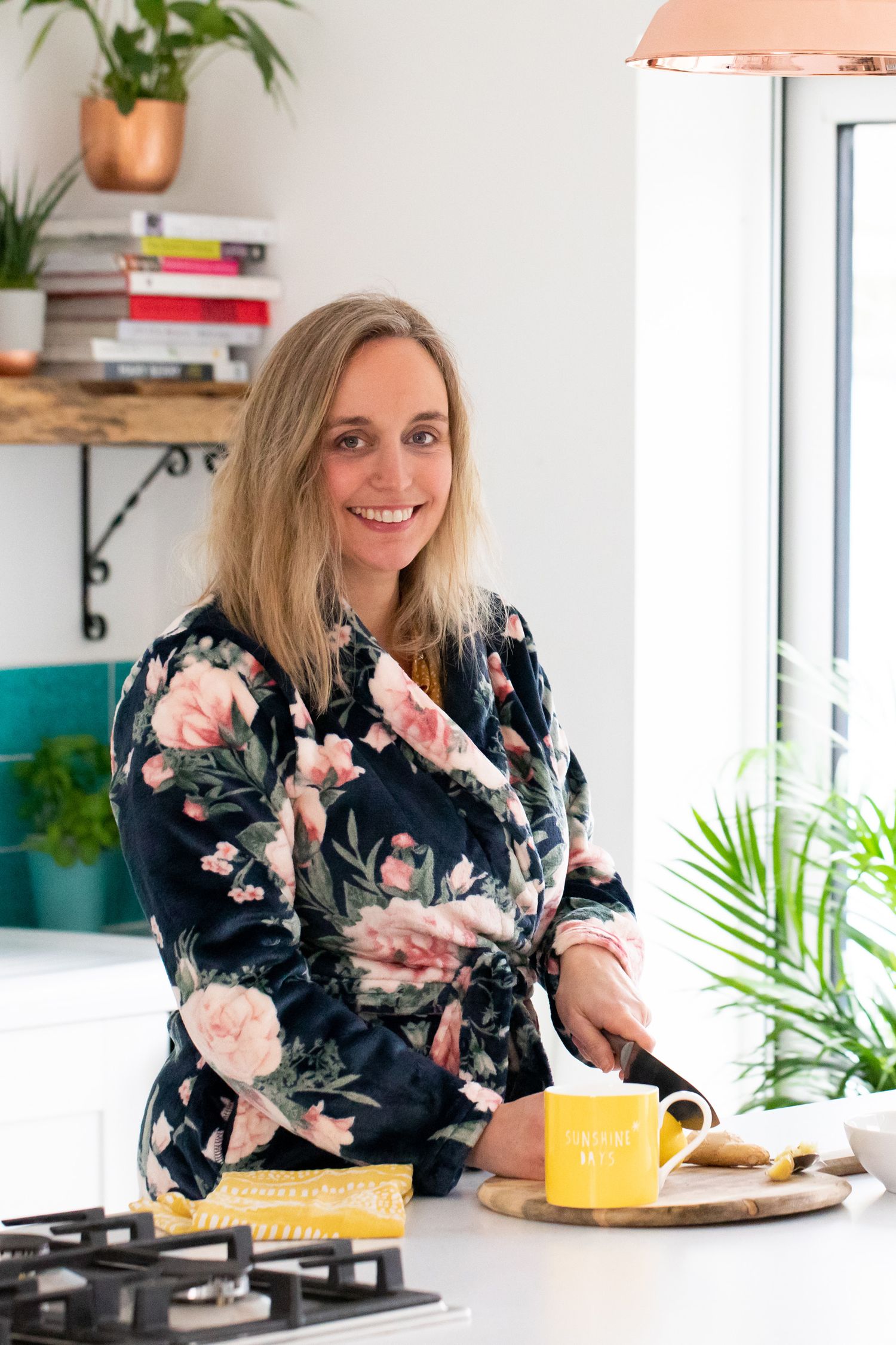 Bright modern kitchen scene with floral dress, copper lighting and yellow coffee mug on counter during business branding photoshoot.