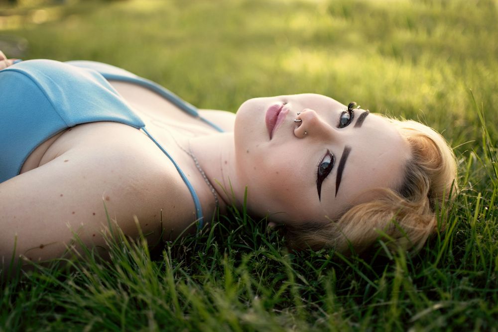 Portrait of someone lying in green grass looking up at the sky.