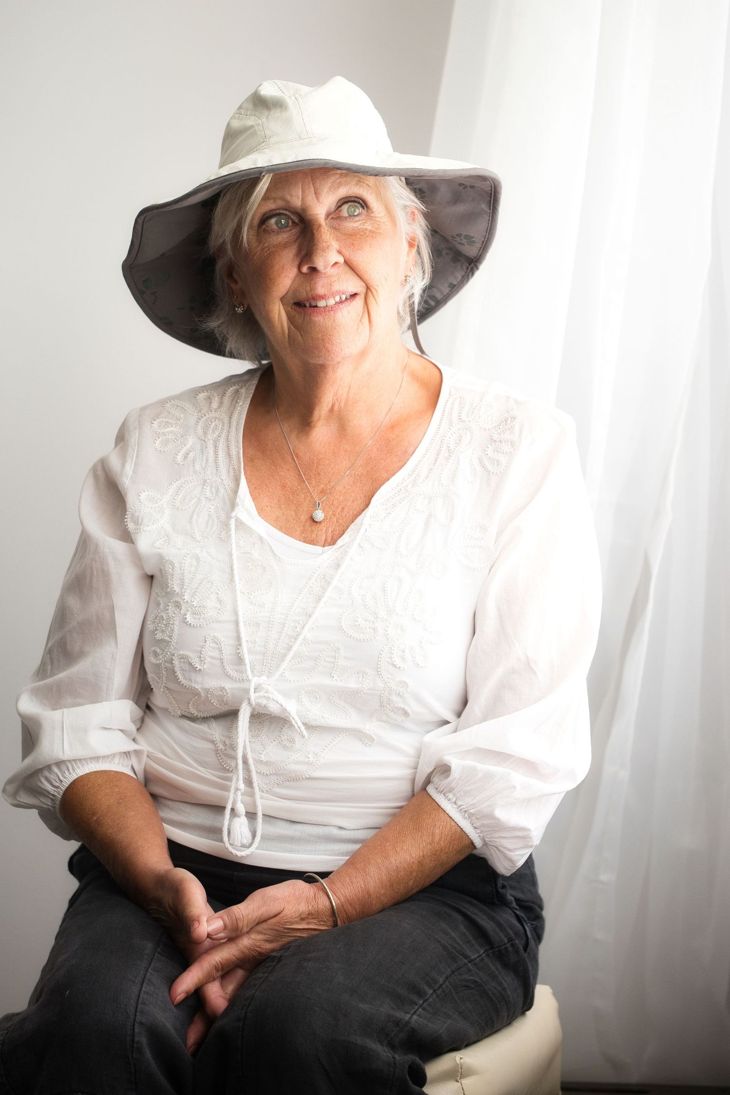 Portrait d'une femme près d'une fenêtre tout en blanc.  Portrait of a woman by a window all in white.