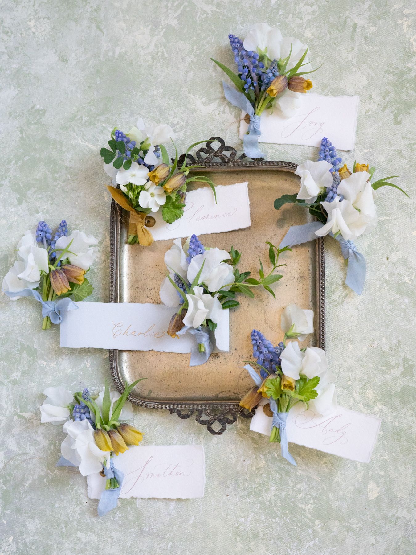 A vintage frame decorated with blue and white flowers and blank name cards on textured background.